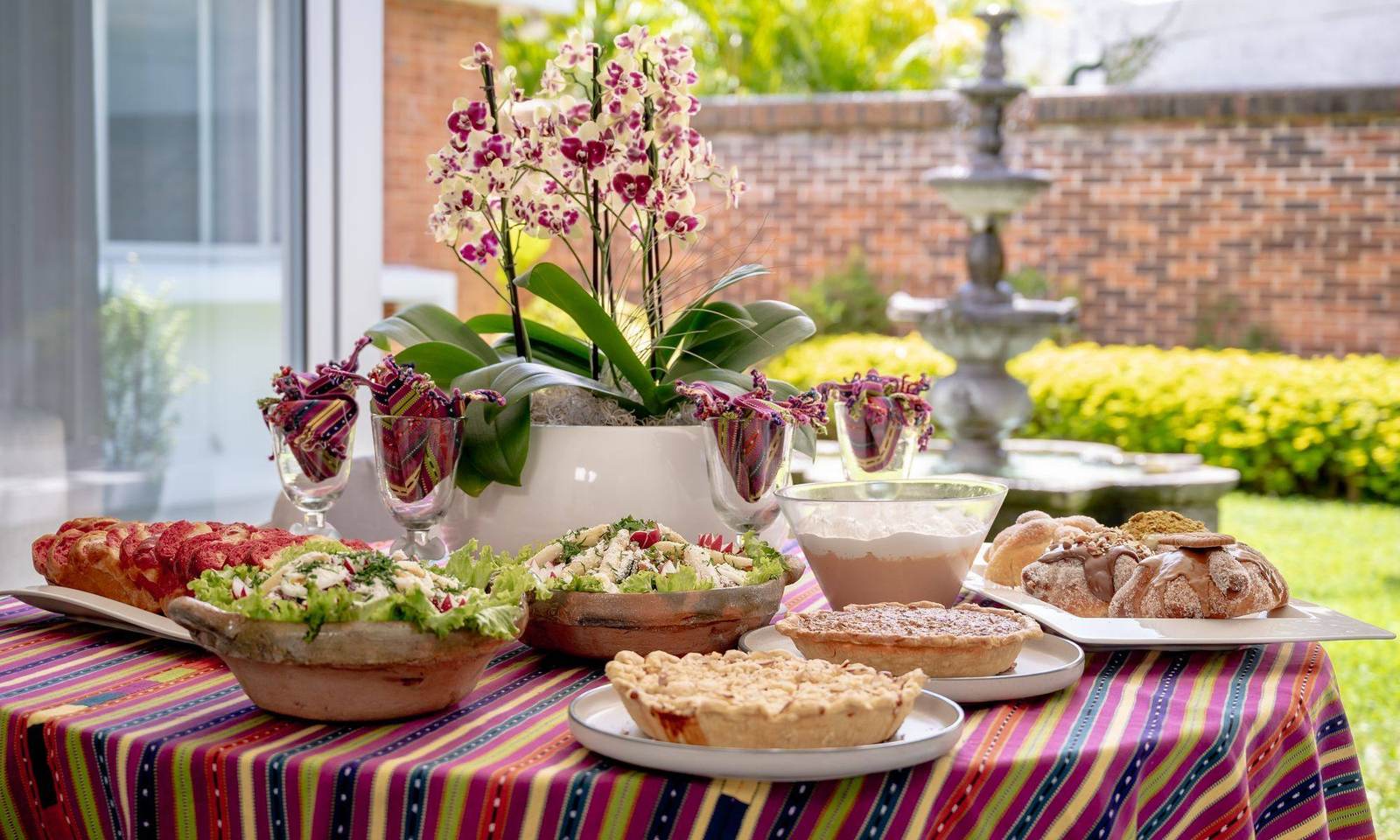 Mesa servida de The Kitchen en el jardín, con orquídeas y tela típica
